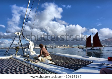 Man works on catamaran\'s desk during sea cruise. Shot near Waterfront, Cape Town, Western Cape, South Africa.