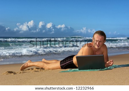 Young businessman lies with notebook on sea beach. Shot in Sodwana Bay nature reserve, KwaZulu-Natal province, Southern Mozambique area, South Africa.