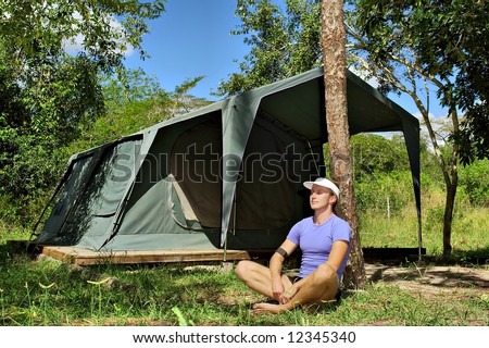 Young hiker meditates under pine tree in camping site. Shot near Sodwana Bay nature reserve, KwaZulu-Natal province, Southern Mozambique area, South Africa.