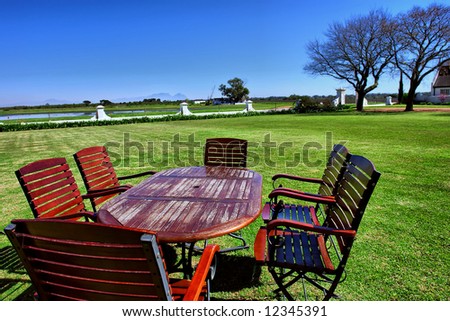 Red table with chairs on restaurant\'s lawn. Shot in wine farms between Stellenbosch and Cape Town, Western Cape,  South Africa.