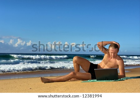 Young businessman works with notebook on beach. Shot in Sodwana Bay nature reserve, KwaZulu-Natal province, Southern Mozambique area, South Africa.