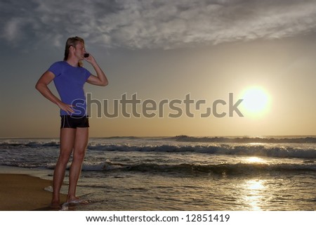 Young man listens over mobile phone standing on beach during sunrise. Shot in Sodwana Bay Nature Reserve, KwaZulu-Natal province, Southern Mozambique area, South Africa.