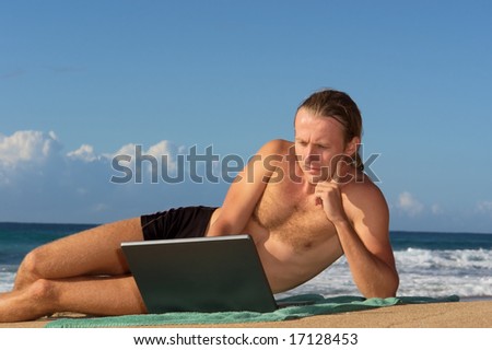 Serious man lying with notebook on beach. Shot in Sodwana Bay nature reserve, KwaZulu-Natal province, Southern Mozambique area, South Africa.