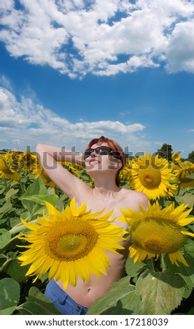 Happy red-hair girl sunbathes among sunflowers. Shot in Ukraine.