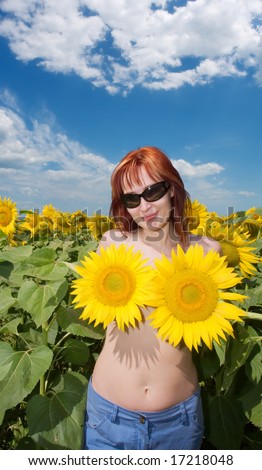 Red-hair girl covers her nipples by sunflowers. Shot in Ukraine.