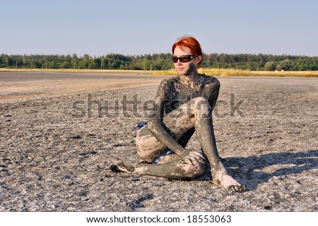 Nude young woman covered by therapeutic muds sits in yoga pose. Shot in Ukraine.
