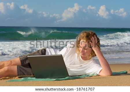 Blonde businesswoman lies with notebook on beach - sunrise light. Shot in Sodwana Bay Nature Reserve, KwaZulu-Natal province, Southern Mozambique area, South Africa.