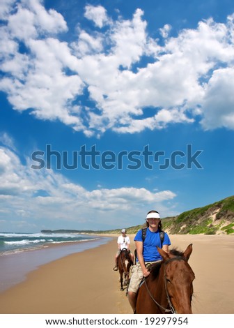 Couple of horse riders on beach under dramatic skies. Shot in Sodwana Bay Nature Reserve, KwaZulu-Natal province, Southern Mozambique area, South Africa.