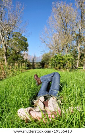 Woman in jeans lies in park on grass. Shot in Vergelegen estate, near Cape Town, Western Cape, South Africa.