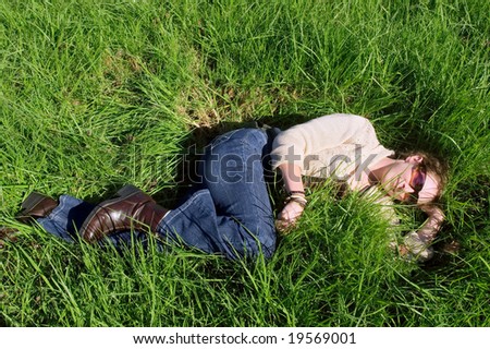 Happy woman relaxing on grass in park. Shot in Vergelegen estate, near Cape Town, Western Cape, South Africa.