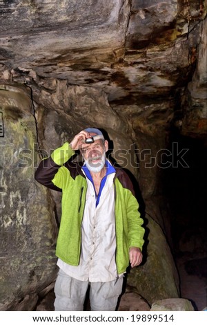 Smiling old man prepares his headlamp in a cave. Shot in Table Mountain Nature Park, near Cape Town, South Africa.