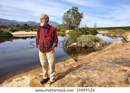 Old man looks at sunset next to river in mountains. Shot next to Olifant (Elephant) river, near Citrusdal, Western Cape, South Africa.