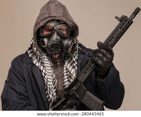 Close up of Post apocalypse man. Doomsday man in gas mask with rifle, trench coat and hood.