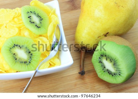 Fresh kiwi, pear and corn flakes in white cup for healthy and light snack.