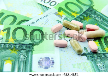 Expensive health care showed with pills and paper money.