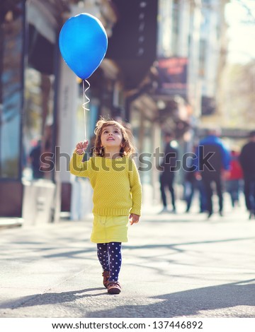 Little Girl walking down the street with a blue balloon