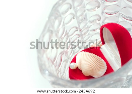 red box with white pearl and shell in a crystal vase. Focal point is on the pearl. Copy space is on the left side of image
