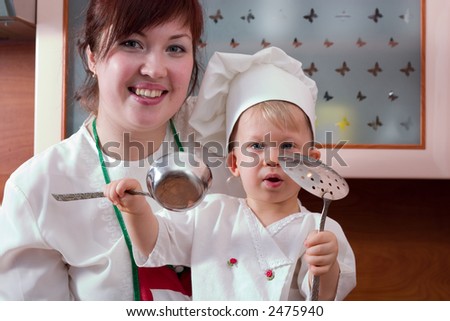 laughing mother and her little son in cook costume at the kitchen