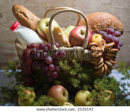 basket with food - apples, cheese, milk, vinegar etc. With wooden wall on the background