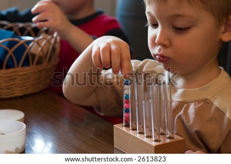 little boy playing with balls and vials in the kindergarten