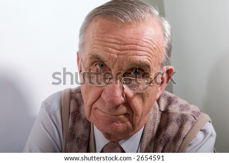 Portrait of concentrated serious old man in glasses