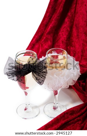 two glasses of champagne with white and black bow knots and red velvet on white background