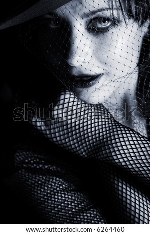 Mysterious low-key portrait of beautiful glamorous woman in hat. Soft-focused. Focus is on eye