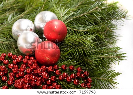 White and red christmas balls and red beads on evergreen background