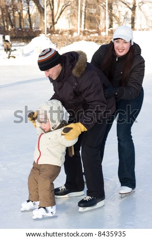 Winter recreation. Family skating on rink. Focus is on boy\'s face, father and mother is a little motion-blurry