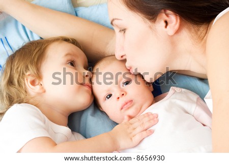 Happy mother with two daughters, kissing and holding them