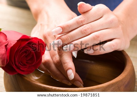 Beautiful fingers with French manicure and red rose