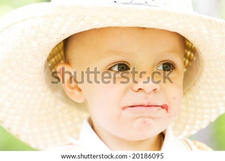 Little boy in the hat with dirty mouth outdoors