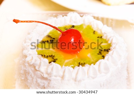 Close-up photo of fancy cake with kiwi and cherry