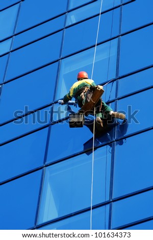 Washer wash the windows of modern skyscraper, high risk work
