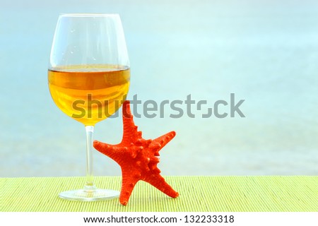 Summer vacation romantic scene with glass of wine and red sea star