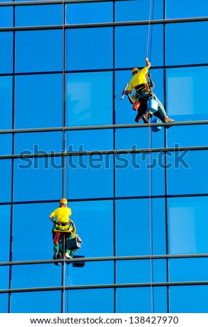 Washers wash the windows of modern skyscraper, high risk work