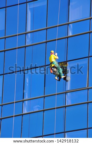 Washer wash the windows of modern skyscraper, high risk work