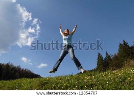 Young and happy attractive female jumping with raised arms, emotion concept