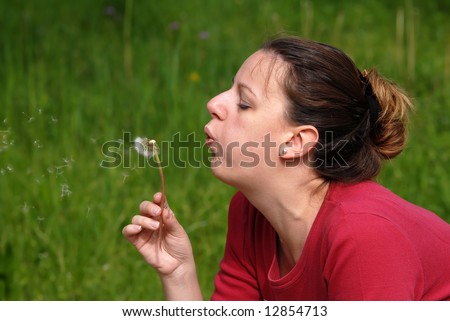 Young attractive female blowing a dandelion, close-up