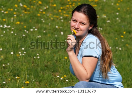 Young attractive female model enjoying flowers in field, close-up