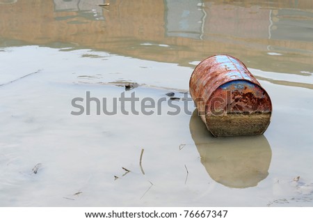 Rusty barrel floating in river, environment pollution concept