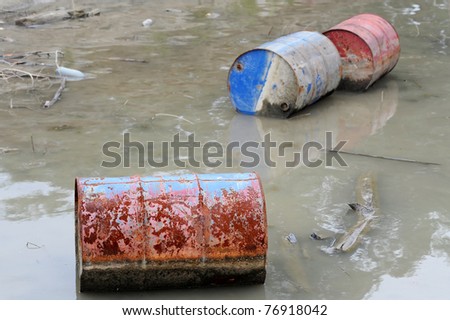 Rusty barrels floating in river, environment pollution concept