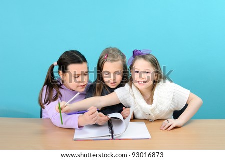 Three happy school girls doing their work in classroom