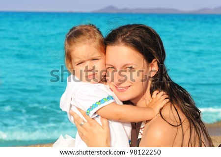 Happy child making funny faces with her mother on the beach, summer vacation concept