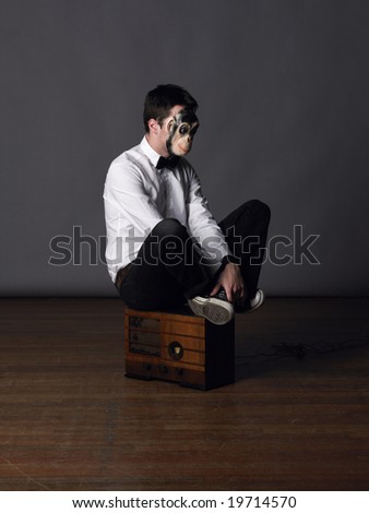 A man in a monkey mask sits on an old radio