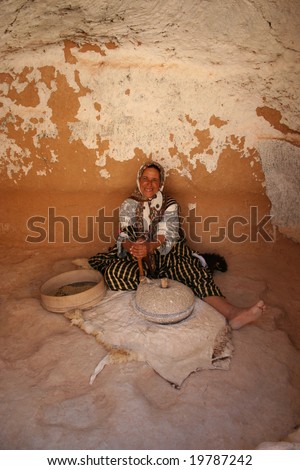 A Happy native woman grinds corn in her house