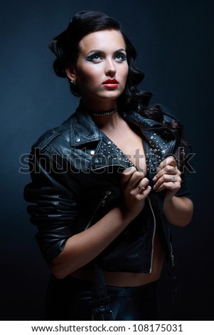 Fetish model in sexy outfit in leather rock jacket. Blue tone
