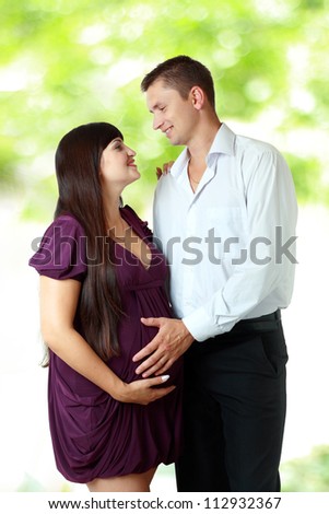 happy couple - beautiful pregnant woman with her husband in the park outdoor