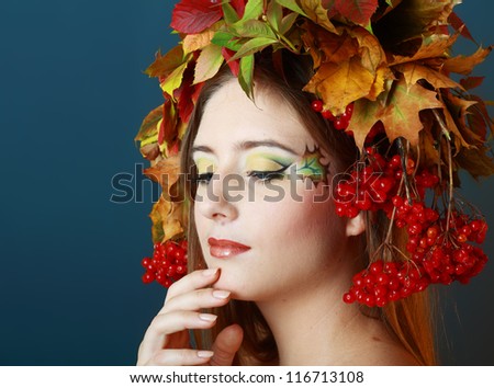 Autumn Woman. Beautiful makeup face art close up and hat from autumn yellow and red leaves