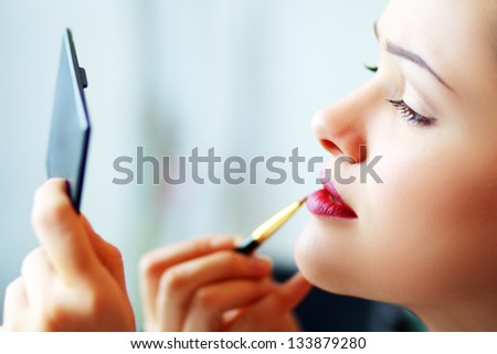 woman applying her make-up in the mirror
